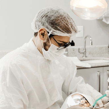 Dentista sorrindo em frente a um paciente