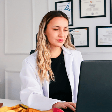Nutricionista de jaleco em frente a um computador