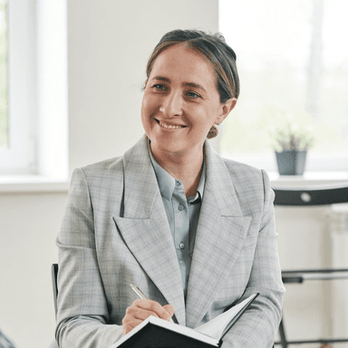 Psicóloga sorrindo em uma consulta segurando um caderno